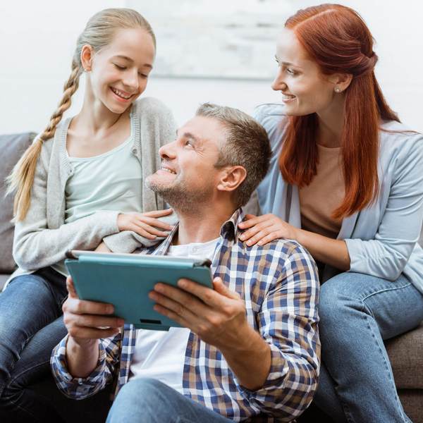 Happy family of three smiling while looking at iPad