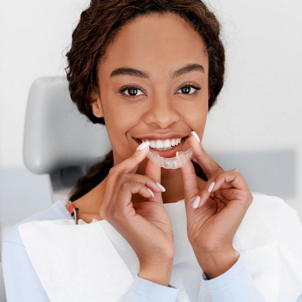 Woman is happily smiling while holding her Invisalign