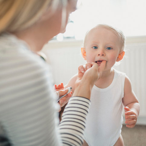 Mother Applies Teething Gel To Her Baby Boy's Mouth