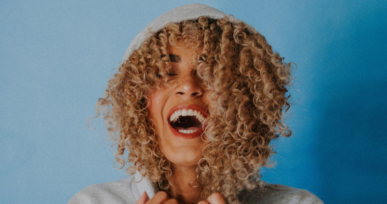 Curly haired woman with a hood on smiling